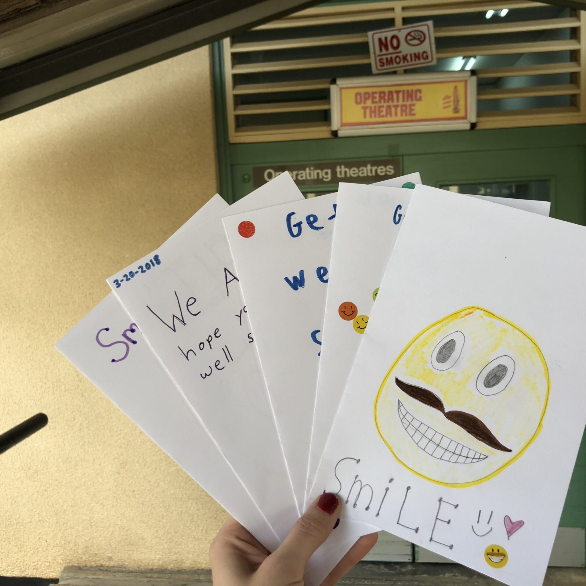 Content Producer Bethany Bogacki holds student-made cards in front of the surgical wing at the Volta Regional Hospital in Ho, Ghana, during a medical mission in 2018. Her student team delivered these cards to patients healing from surgery. (Photo by Bethany Bogacki)